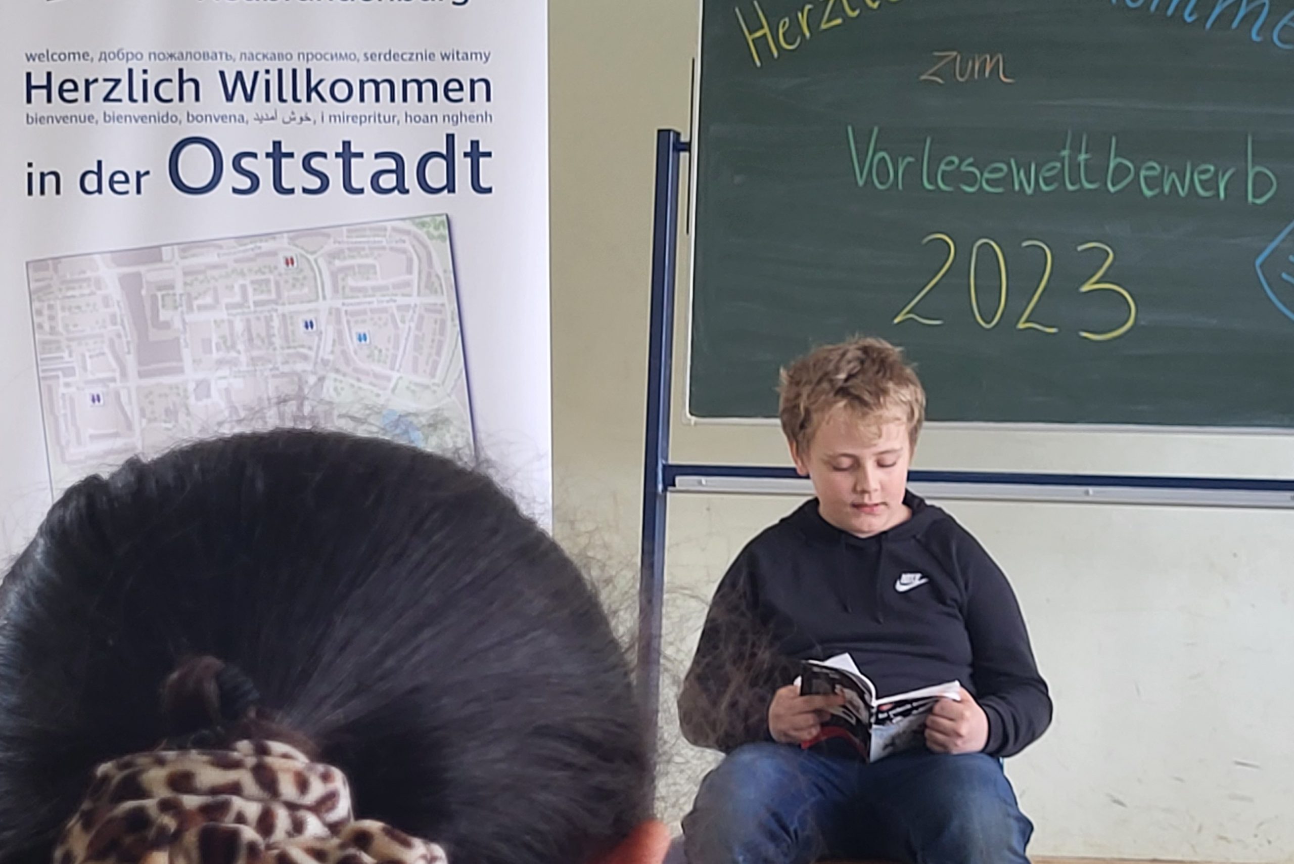 Ein Kind liest vor der Klasse vor im Rahmen des Vorlesewettbewerbs Oststadt 2023