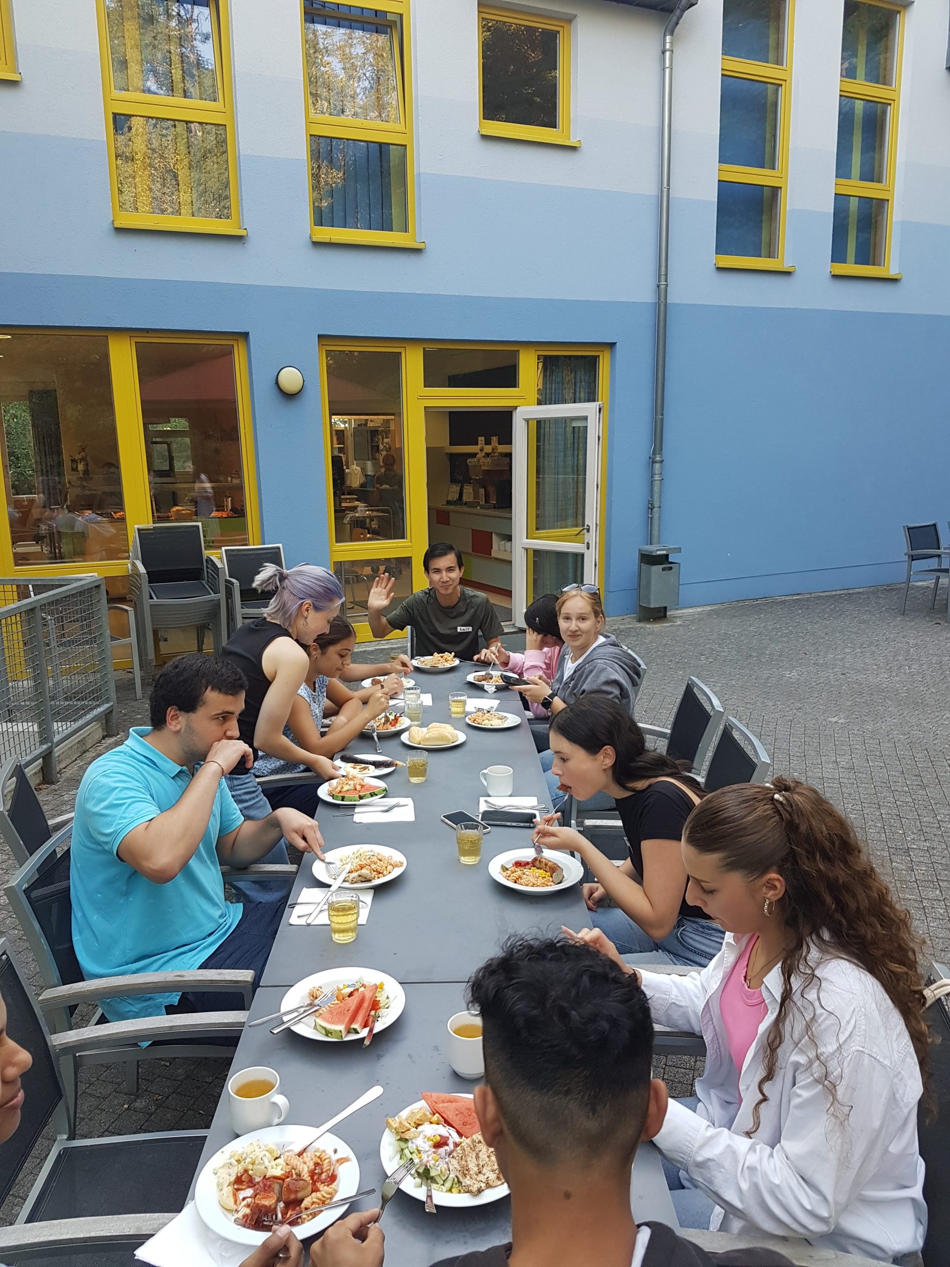Die Stipendiat*innen sitzen im Hof der Jugendherberge und essen gemeinsam Abendbrot.