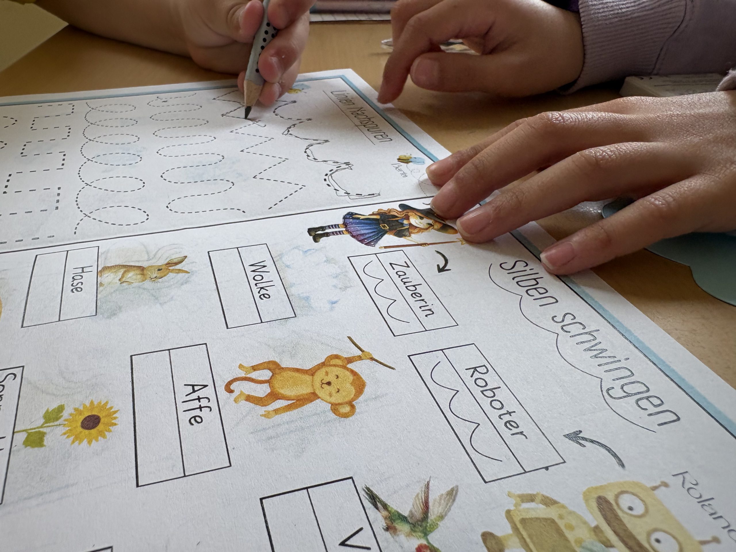 Schulkind hilft Vorschullkind bei Schwungübungen