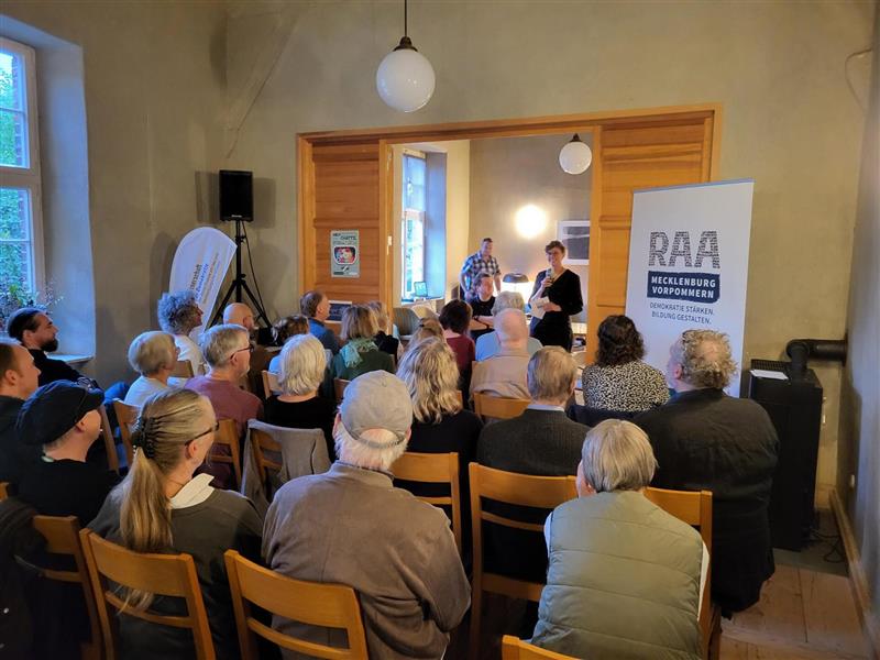 Alena E. Lyons steht vor dem Publikum und stellt Ilko-Sascha Kowalczuk, der vor den Gästen sitzt, vor.